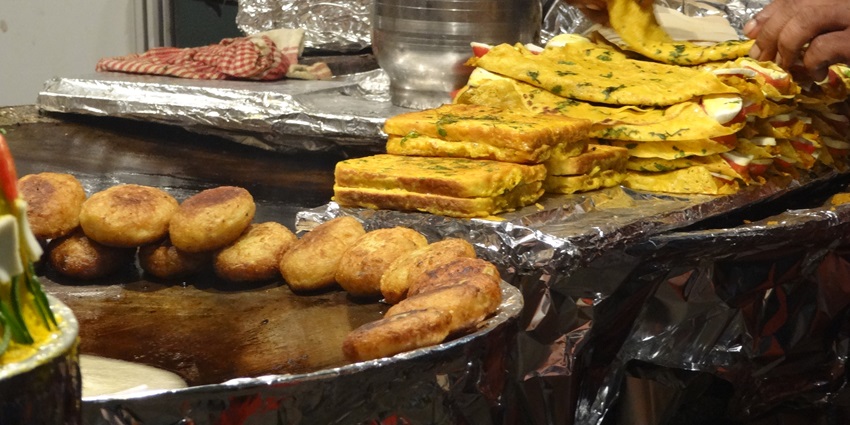 A picture of a street food shop with delicious bread pakoras arranged around a wok