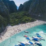 An aerial view of lush greenery, turquoise-blue waters, and golden beaches of Thailand.