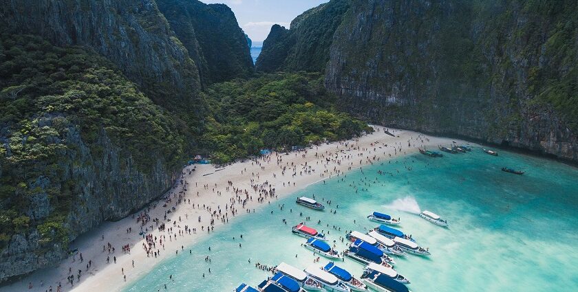 An aerial view of lush greenery, turquoise-blue waters, and golden beaches of Thailand.