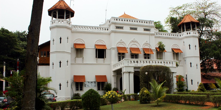 A frontal view of a museum with white exterior walls and a garden area in front