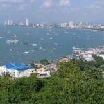 An aerial view of the Pattaya city shore with a lot of buildings on the land and multiple boats in the sea