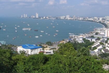 An aerial view of the Pattaya city shore with a lot of buildings on the land and multiple boats in the sea