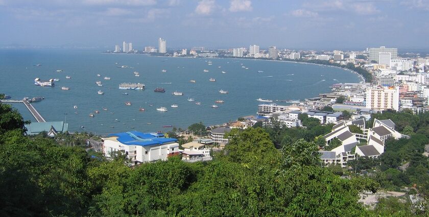 An aerial view of the Pattaya city shore with a lot of buildings on the land and multiple boats in the sea