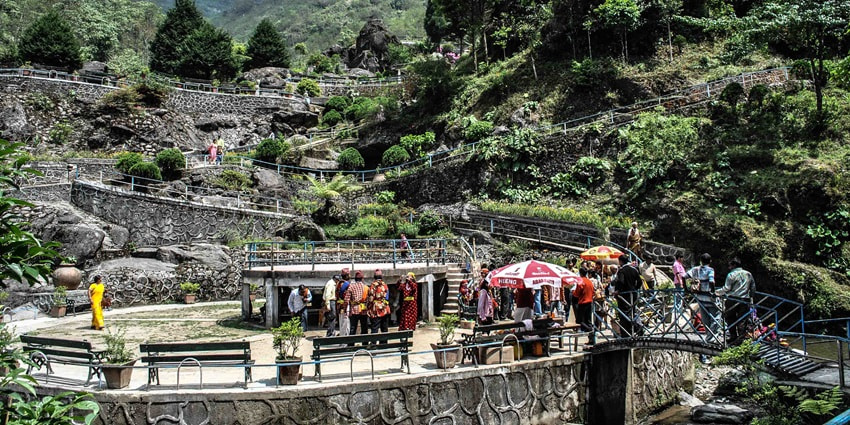 A distant picture of a rock garden in Sikkim with lush green surroundings and a calm ambience