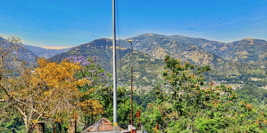 A picture of a traditional Hindu temple in Himachal Pradesh, with lush hills in the background