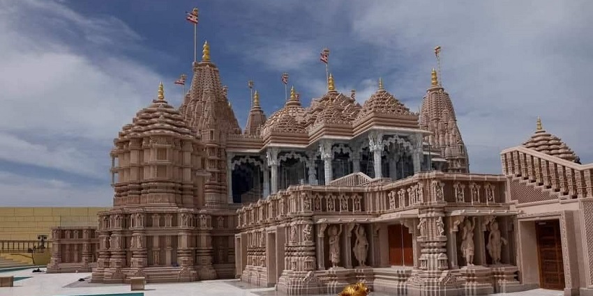 A picture of a temple built using traditional Hindu architecture with a small pond in front