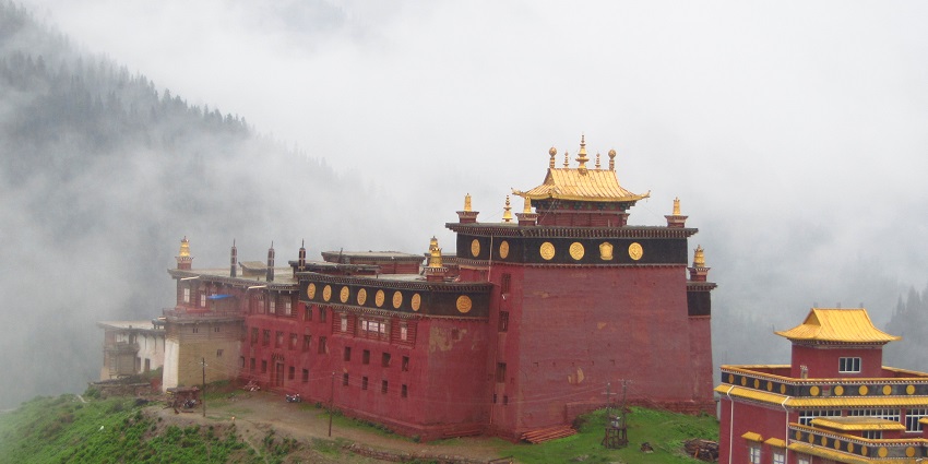 A picture of a monastery in a hilly area taken from the backside with a dense foggy background