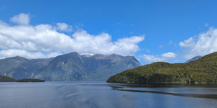 The beautiful view of a lake surrounded by the idyllic landscape and green hills