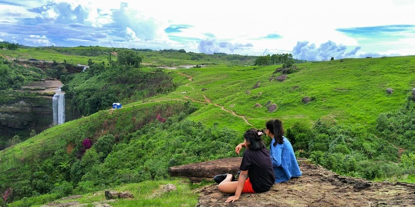 Beautiful view of Shillong with two girls sitting on a rock & enjoying the natural beauty.