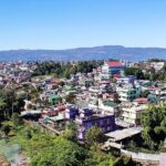 A picture taken from a hill showing the lower city of Shillong during day time