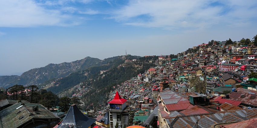 A picture taken from a hill in Shimla capturing the lower city and mountains in background