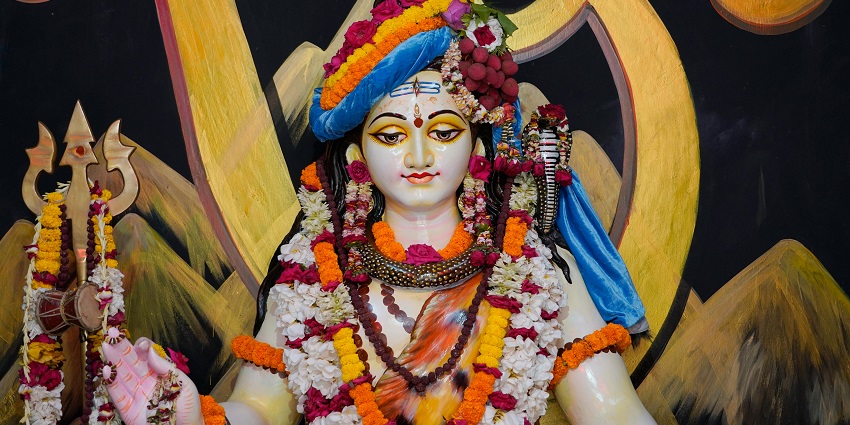A majestic statue of Shiva, intricately carved, surrounded by lush greenery - Nallur Temple.