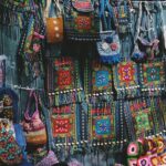 A vibrant view of a shop with colourful crossbody bags and dolls displayed in the front.