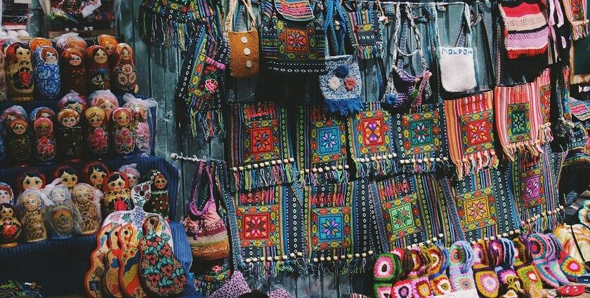 A vibrant view of a shop with colourful crossbody bags and dolls displayed in the front.