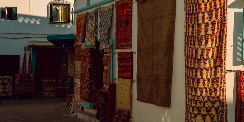 An amazing view of beautiful carpets hanging on the wall of a shop in a market in Morocco