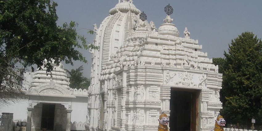 A picture of a temple in Delhi made of white marble with 2 sculptures on the entrance