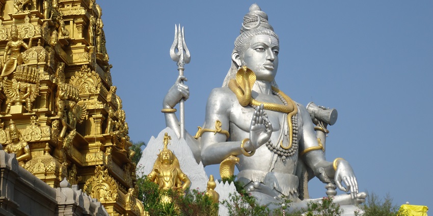 A picture of a tall Shiva statue in Murudeshwar, sitting beside a golden temple