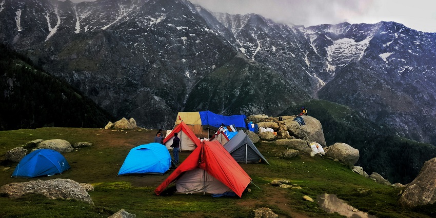An awe-inspiring view of snow-capped mountains and lush green fields in Himachal Pradesh.