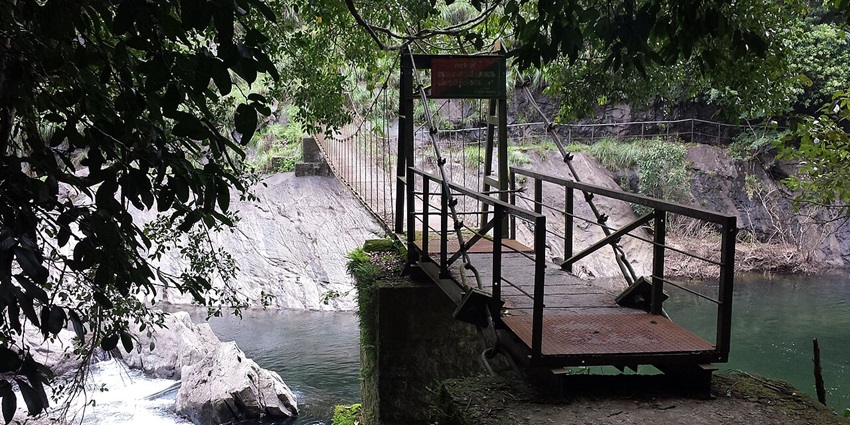 A bridge crossing a stream in Silent Valley National Park, Kerala, surrounded by rainforest.