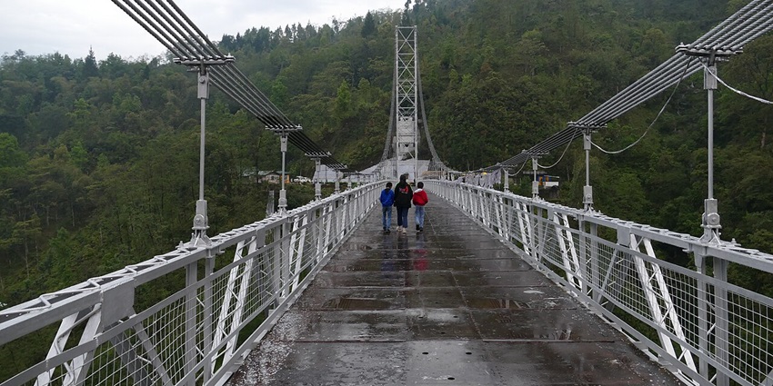 View of Singshore Bridge showcasing its towering height over a deep gorge, surrounded by hills