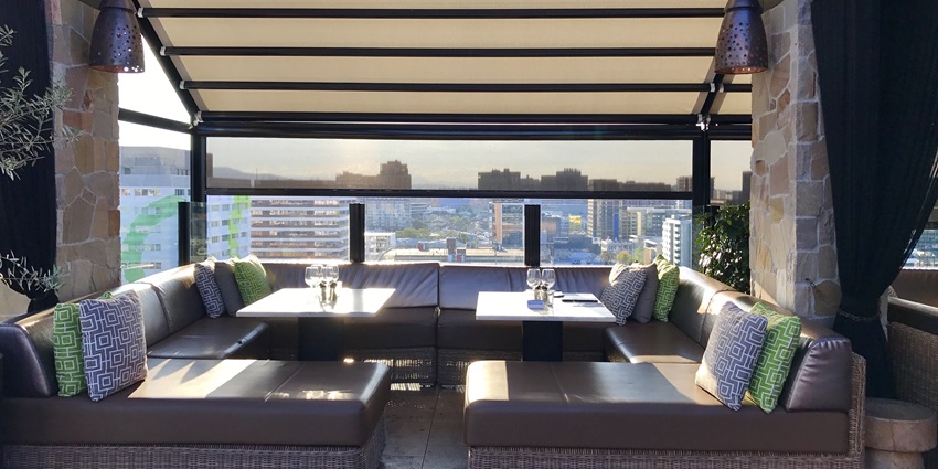 A picture of a rooftop bar with a cosy setting, giving a 360 degree view of the city