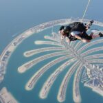 A breathtaking aerial view of people skydiving over Palm Jumeirah during the daytime.