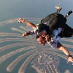 A mesmerising aerial view of two people skydiving over Dubai during the daytime.