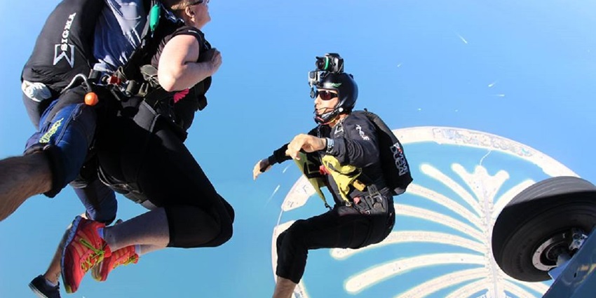 A picture of a guided skydiving experience in Dubai with divers floating mid-air and Palm Islands visible in the background
