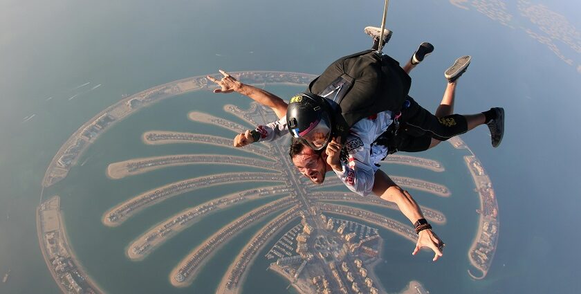 A mesmerising aerial view of two people skydiving over Dubai during the daytime.