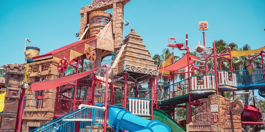 Slides of a waterpark, twisting and turning, offering rides and splashes into clear pools.