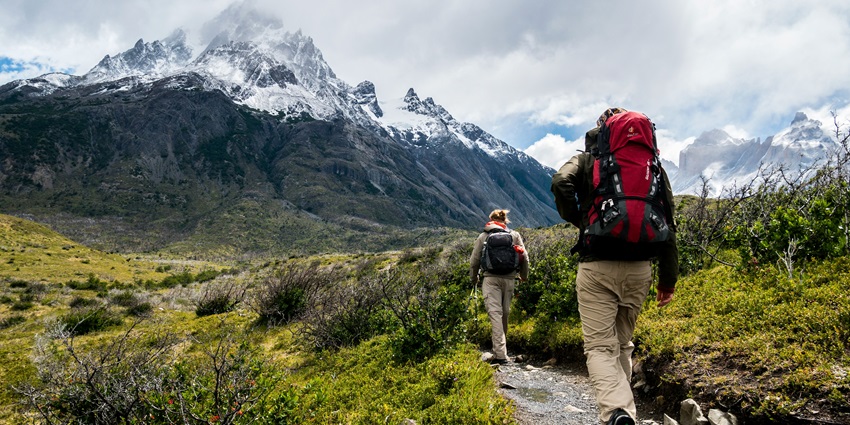 A view of two hikers making their way through the rustic routes surrounded by peaks.
