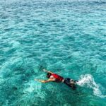 A glimpse of a person swimming in the turquoise-blue waters of the majestic sea.