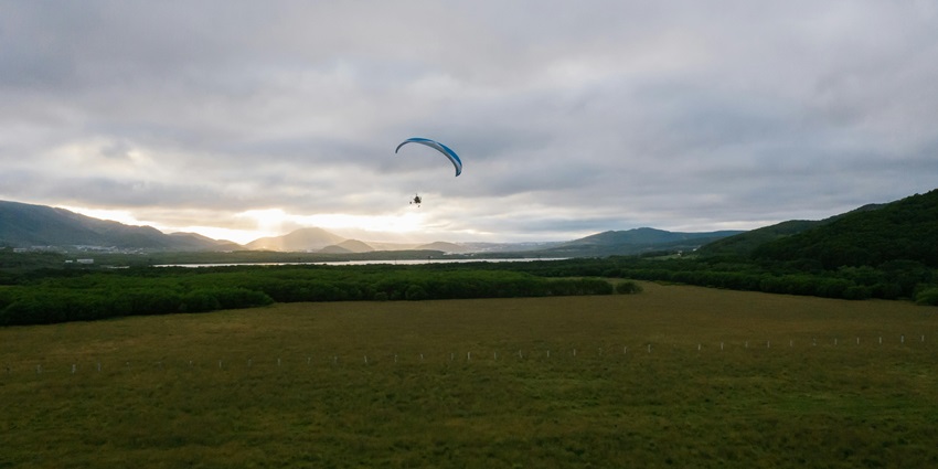 A Person Paragliding over a Grassy Field - best places for paragliding in Kashmir.