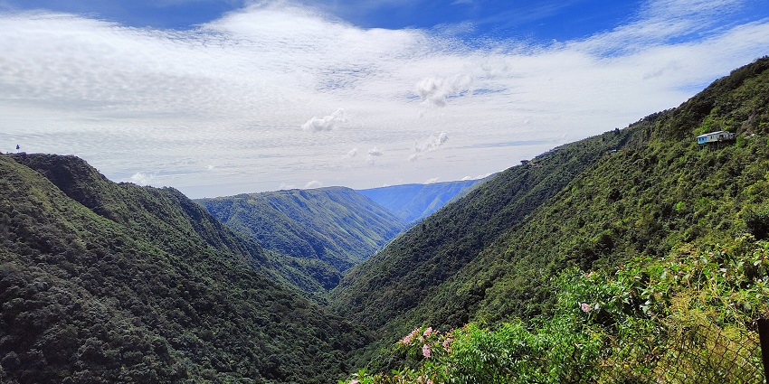 Scenic view of Sohra (Cherrapunji) with rolling green hills, mist, and cloudy sky.
