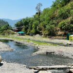 A stunning view of a water body in Solan with lush green surroundings and mountains.