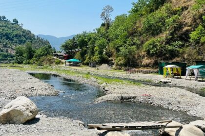 A stunning view of a water body in Solan with lush green surroundings and mountains.