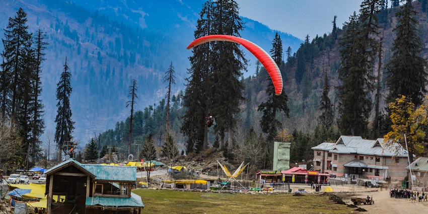 A beautiful scenic image of a paraglider, gliding in the Solang Valley near Kalath