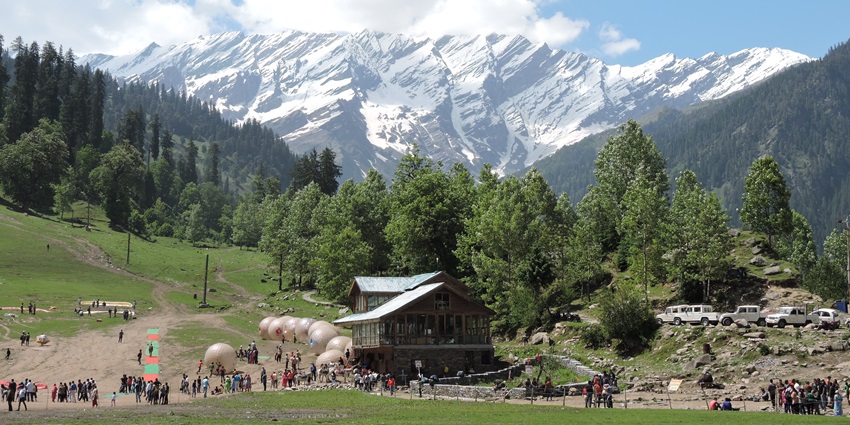 Tourists enjoying adventure sports like paragliding and skiing at Solang Valley, a picturesque destination.