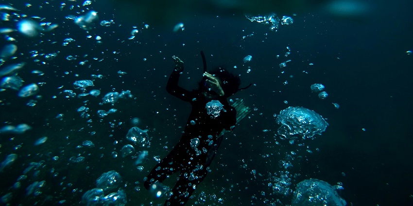 Man swimming underwater, exploring the ocean while scuba diving in Vietnam.