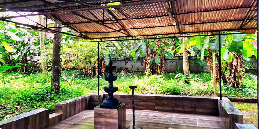 A picture of a shed in a temple compound with a Shiva lingam in the centre