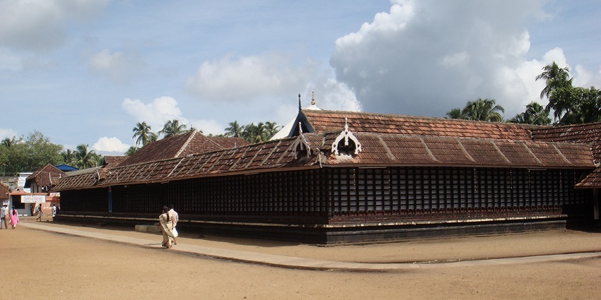 A temple premises captured from a short distance with pilgrims walking