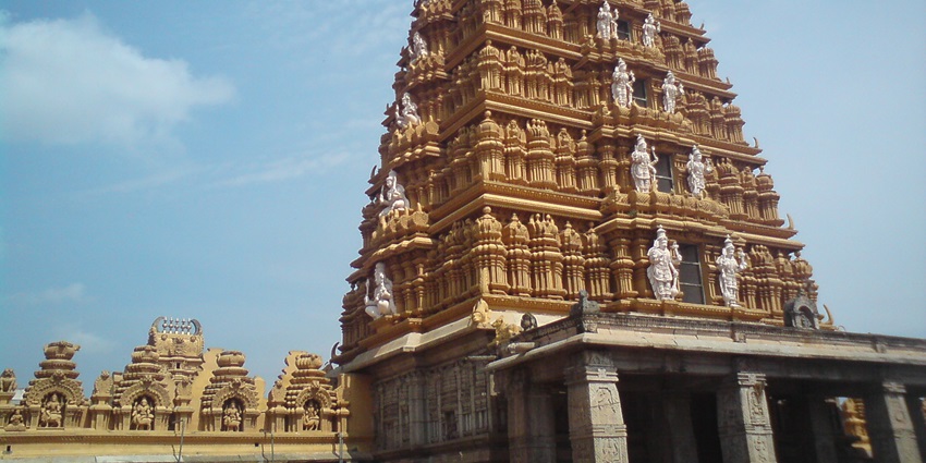 A picture of a temple in Kerala with intricate wall carvings and a tall Gopurama