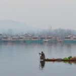 View of man selling vegetables and fruits on a Shikara in Dal Lake with a scenic backdrop