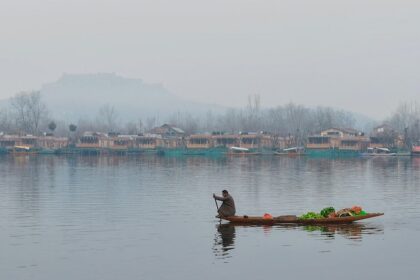 View of man selling vegetables and fruits on a Shikara in Dal Lake with a scenic backdrop