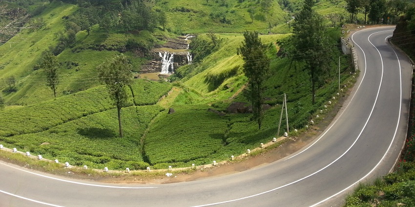 A stunning view of St. Clair's Waterfall in Sri Lanka, surrounded by lush greenery and mist.