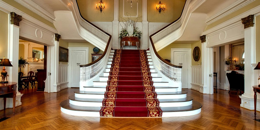 View of a staircase with wooden flooring at a hotel with a chandelier hanging to ceiling.