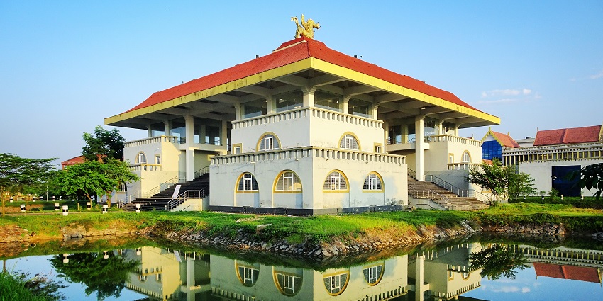 A picture of a traditionally architectured building with its reflection in a pond of water in front during daytime