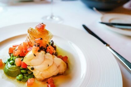 A lip-smacking view of a ceramic white plate served with a seafood meal on a table.