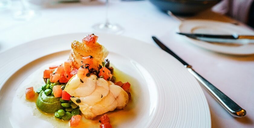 A lip-smacking view of a ceramic white plate served with a seafood meal on a table.