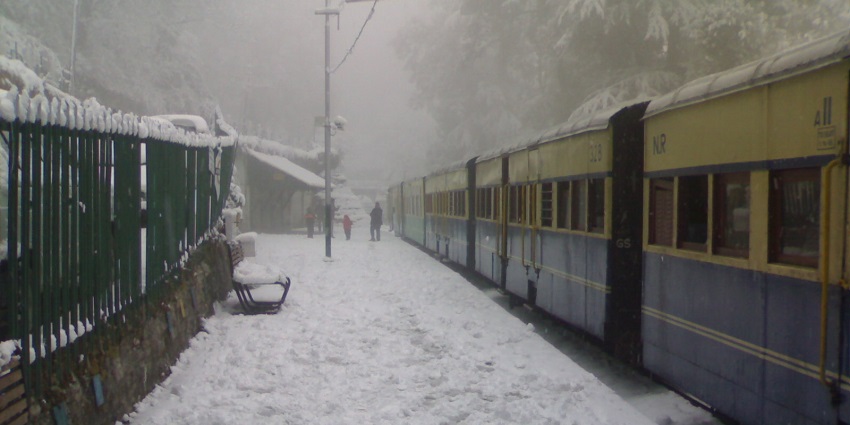 Snow covered trails of Summer hill railway station, with tourist walking by on a foggy day